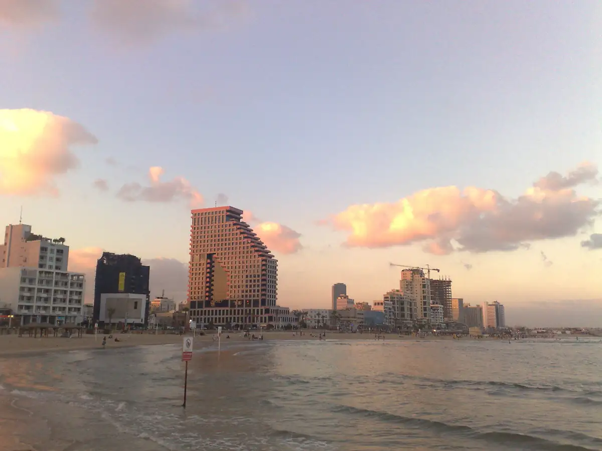 חוף הים של תל אביב עם שחר, מגדלי המלונות ועננים ורודים